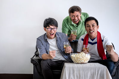 Fans enjoying beer while watching sports on tv at home