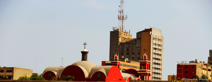 Church and buildings against clear sky on sunny day