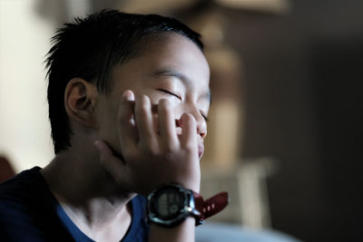 Close-up of boy wearing wrist watch sleeping indoors