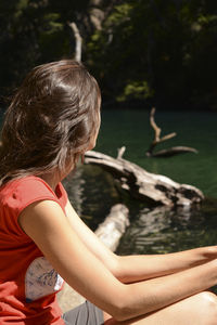 Rear view of girl sitting against water