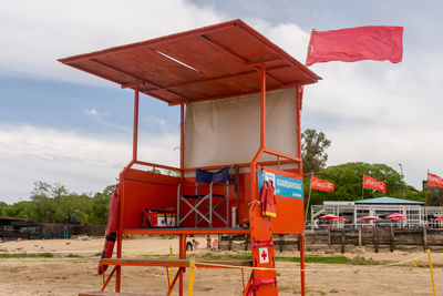 Red hut on beach against sky