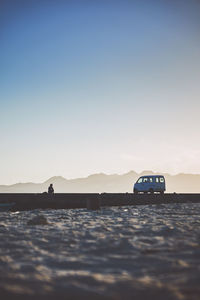 Vehicle on landscape against clear sky during sunset