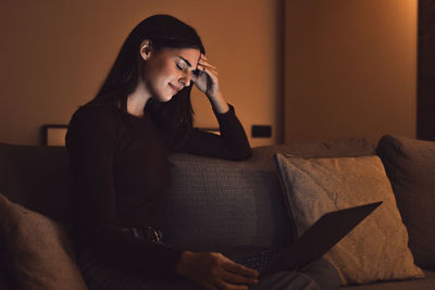 Young man using mobile phone while sitting on sofa at home