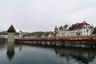 View of buildings by river against cloudy sky