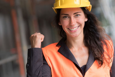 Cheerful and beautiful female engineer showing hurrah gesture