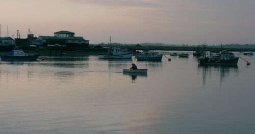 Boats moored at harbor against sky