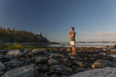 Full length of man standing on rock at beach against sky