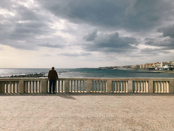 Rear view of man looking at sea against sky