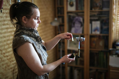 The master woman near the bench works with tools, on the torch boils water with a metal plate. 