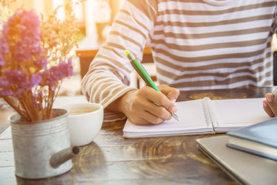 Midsection of man holding coffee cup on table