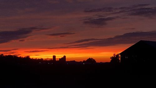 Silhouette buildings against orange sky