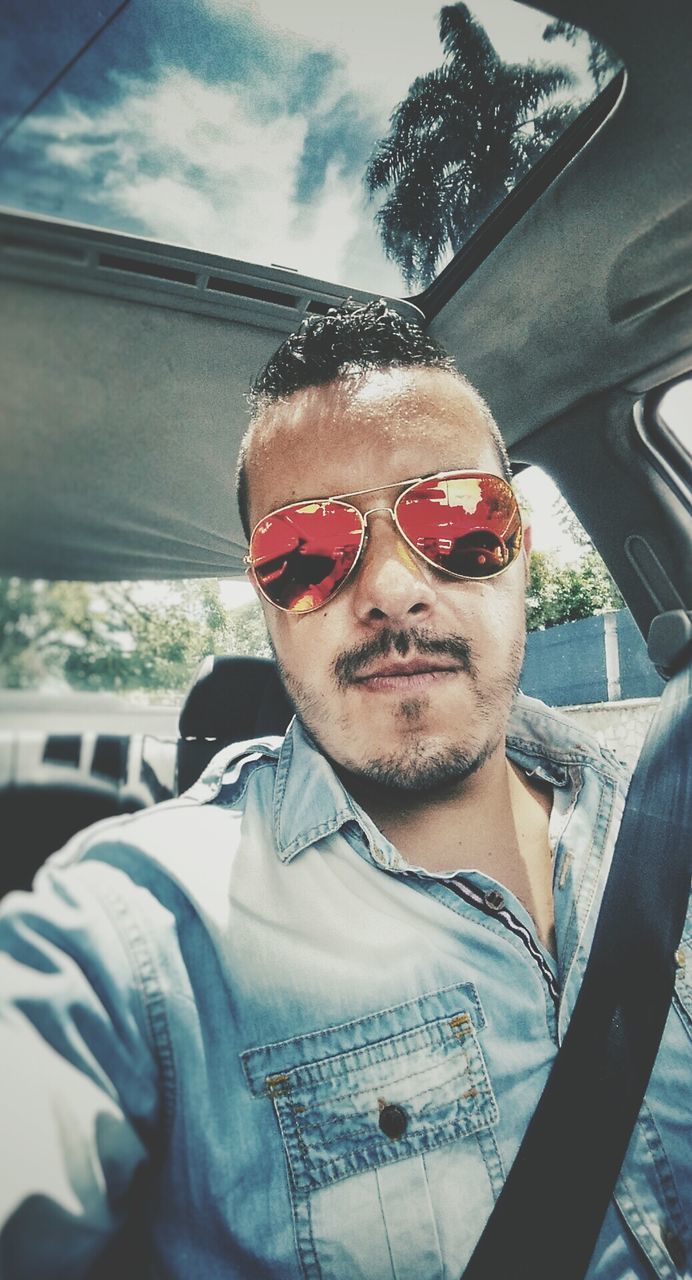 transportation, portrait, mode of transport, sunglasses, looking at camera, person, young men, lifestyles, young adult, vehicle interior, car, land vehicle, leisure activity, front view, headshot, travel, car interior, close-up