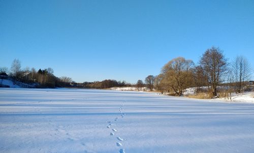 Snow covered field against clear sky