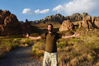 Portrait of man with arms outstretched standing on field