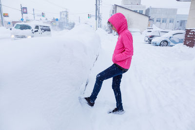 Woman with umbrella on snow covered car