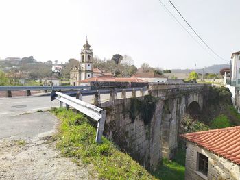 Arch bridge by buildings against sky in city