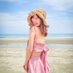 Portrait of woman wearing hat on beach against sky