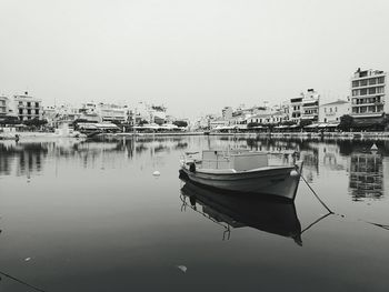 Boat moored in river against sky in city