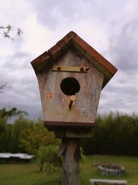 Close-up of birdhouse on wooden post against sky