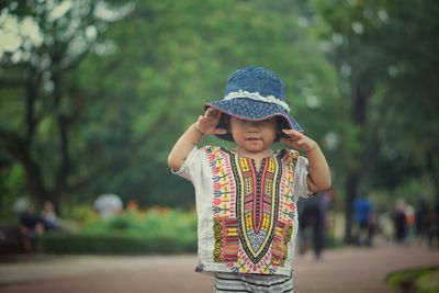 Portrait of cute girl wearing hat while standing on road 