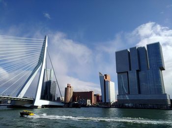 Modern buildings by river against sky in city