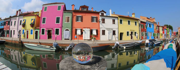 Boats in canal by buildings against sky in city