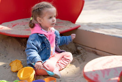 Full length of cute girl playing while sitting on sand