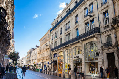 People walking on street amidst buildings in city