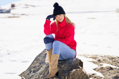 Rear view of woman on rock at beach during winter