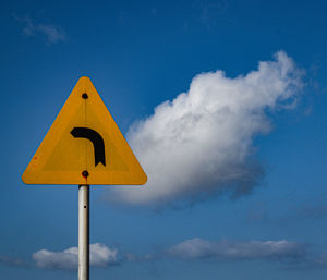 Low angle view of road sign against blue sky