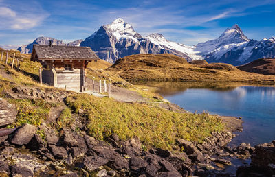 Scenic view of lake by snowcapped mountains against sky