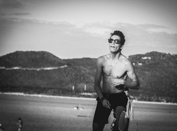 Portrait of young man wearing sunglasses against mountain