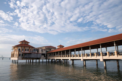 Houses in sea against cloudy sky