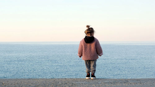 Rear view of man standing by sea against sky