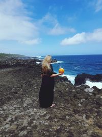 Woman standing at beach against blue sky