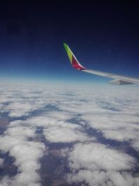 Airplane flying over cloudscape against blue sky