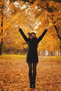 Happy woman throwing autumn leaves at park