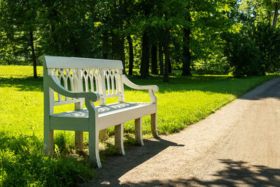 Beautiful white wooden historic bench in a shady park on a summer day. selective focus.