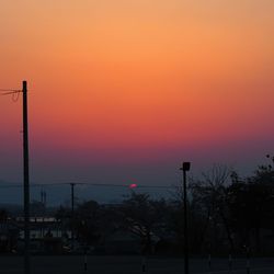 Silhouette trees by sea against orange sky