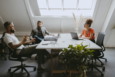 Female and male colleagues discussing during office meeting in boardroom