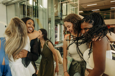 Happy teenage girls greeting each other while enjoying in mall