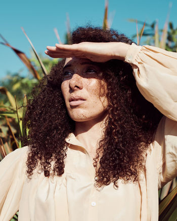 Close-up of woman shielding eyes against plants