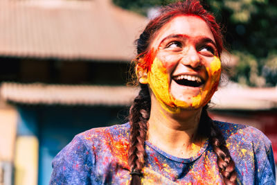 Happy young woman with powder paint on face during holi