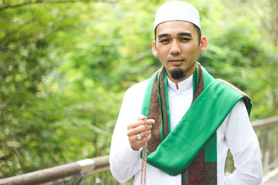 Portrait of mid adult man praying while standing by railing at park