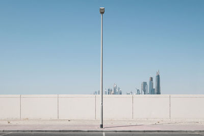 Street and buildings against clear blue sky