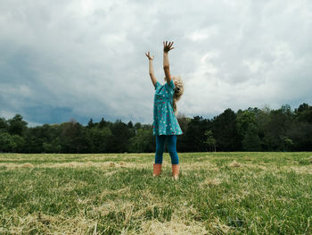 Little girl child stand on meadow with hands up to sky in hope. freedom, innocence and adolescense 