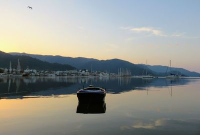 Sailboats moored on lake against sky during sunset