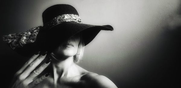 Portrait of woman wearing hat against wall