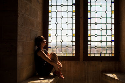 Young woman looking through window