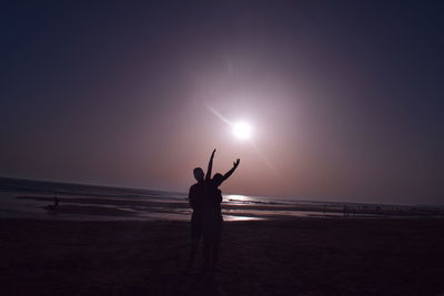 Silhouette man standing on beach against sky during sunset